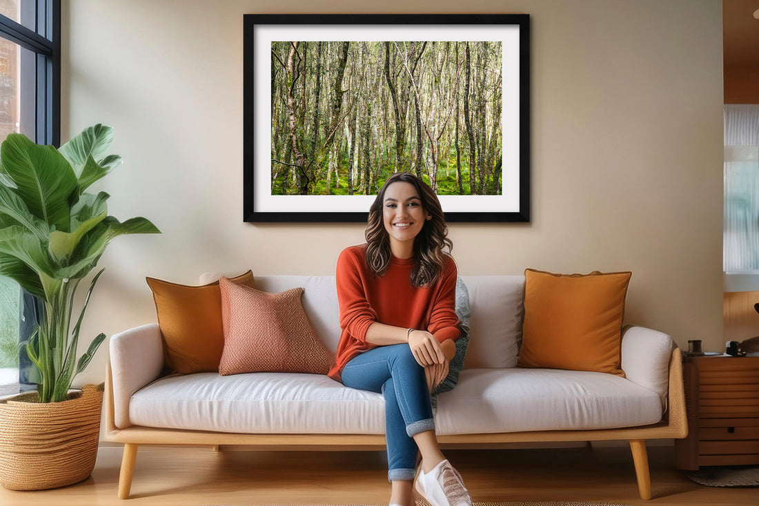 art is good for you blog image. A happy woman is sitting on a sofa in a brighly lit living room with a fine art print hanging on the wall behind her