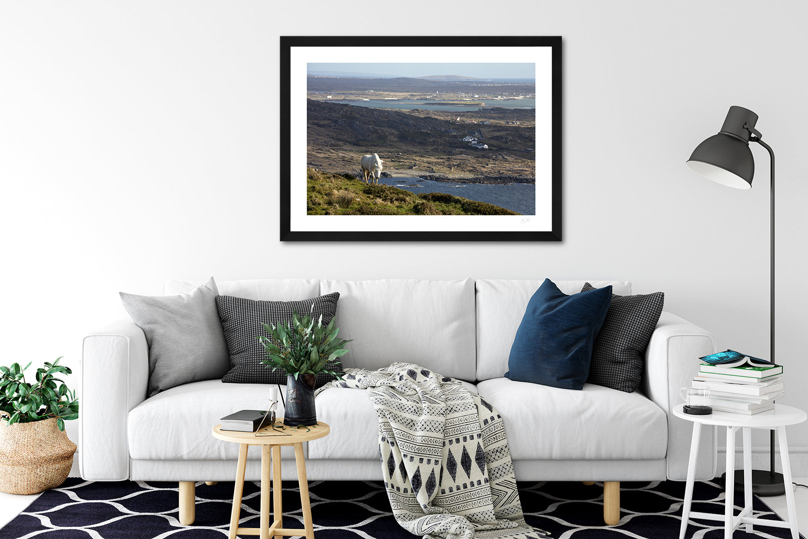 a framed fine art photographic print of a connemara pony overlooking the connemara coastline hanging on a living room wall above a sofa, available to buy online