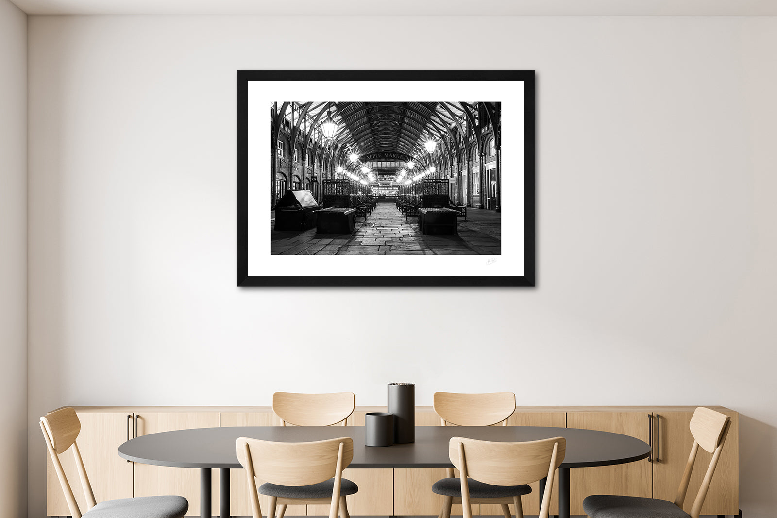 a framed black and white fine art photographic print of the Apple Market in Covent Garden, London, England, after the market has closed, hanging on a dining room wall