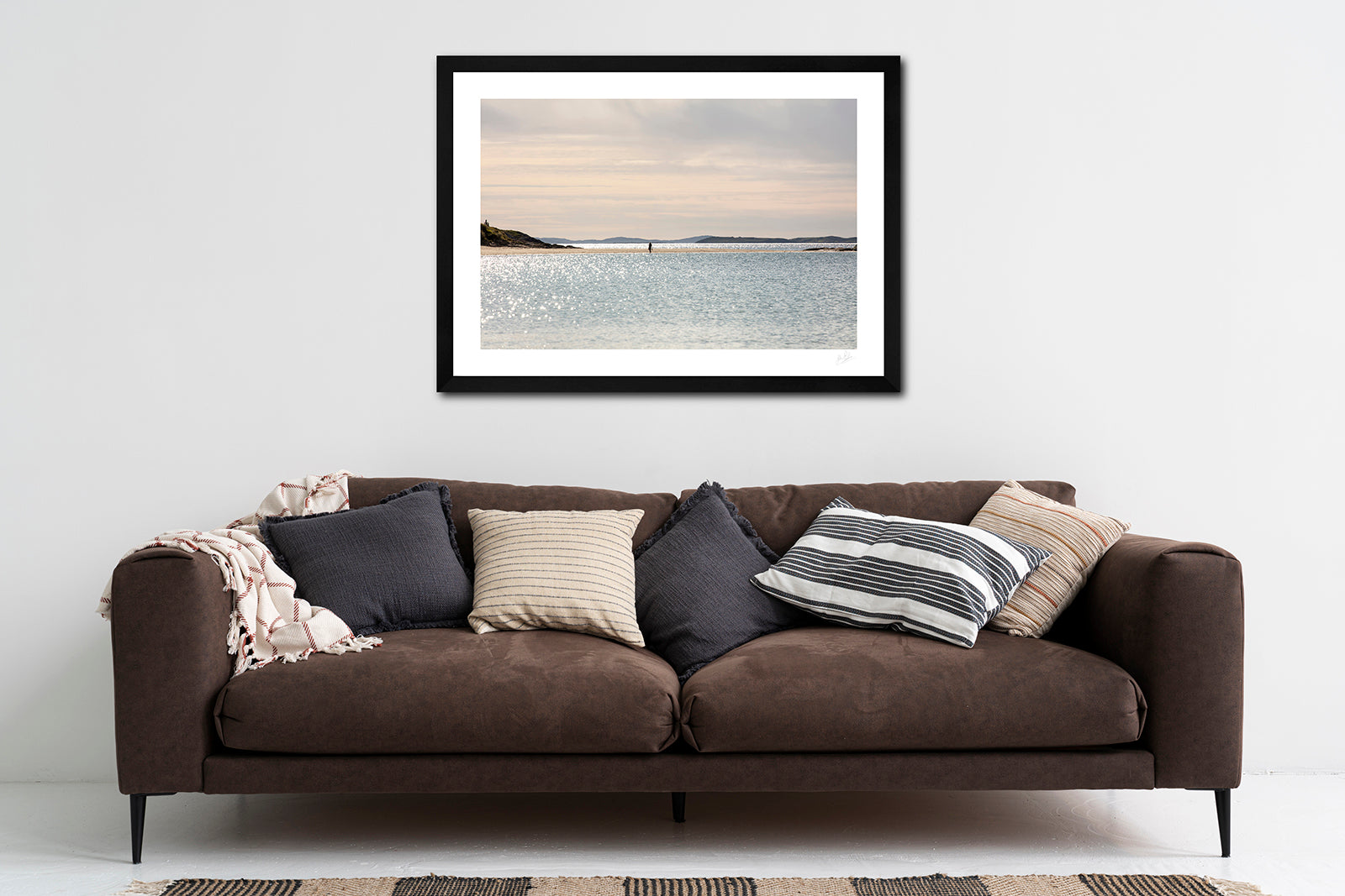 a framed fine art photographic print of a young woman taking a leisurely stroll along a quiet Glassilaun Beach in Connemara, Ireland on a beautiful summer afternoon, hanging on a wall above a sofa