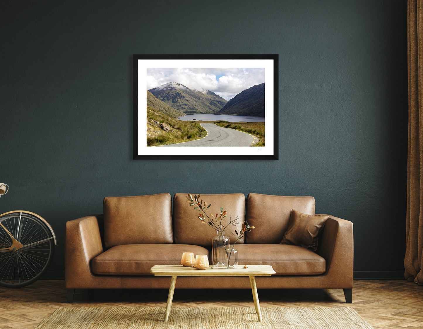 a framed fine art photographic print of Doolough Valley and the surrounding mountains in Mayo, hanging on a wall above a brown leather sofa