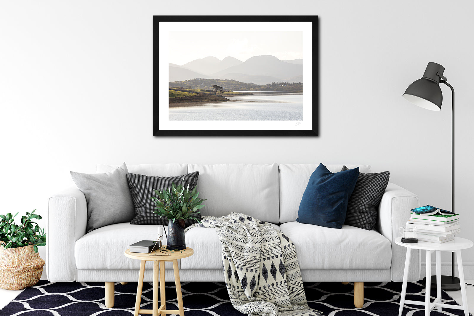 a framed fine art photographic print looking across Ballynakill Lough, Connemara to the 12 Bens mountain range on a bright summer morning, hanging on a wall above a white sofa