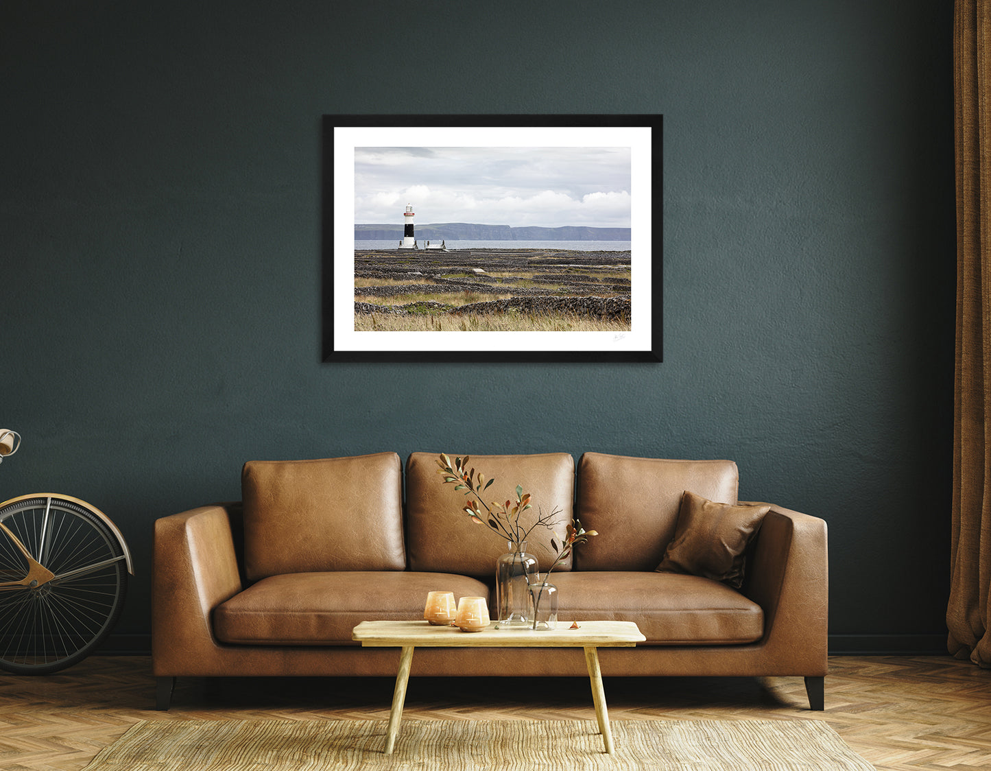 a framed fine art photographic print of Inisheer Island's famous dry stone walls surrounding the lighthouse while the Cliffs of Moher are visible in the background, hanging on a wall above a brown sofa