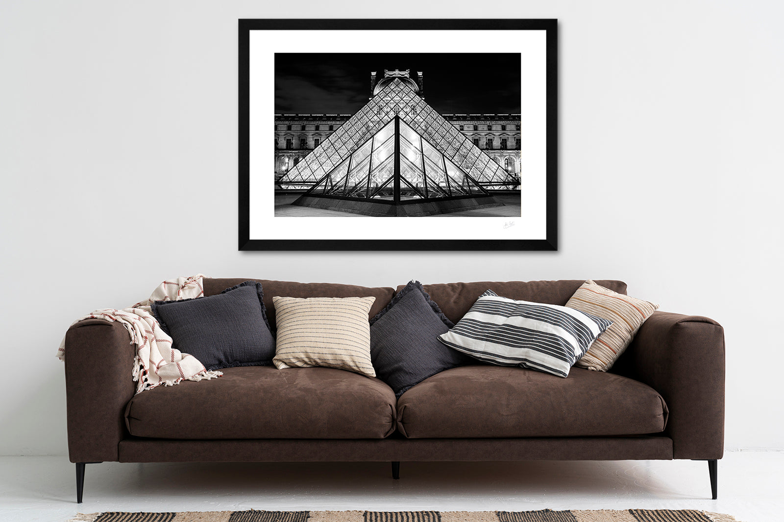 framed black and white fine art print of the pyramids at the side entrance to the Louvre Museum lined up in perfect symmetry on a living room wall above a sofa