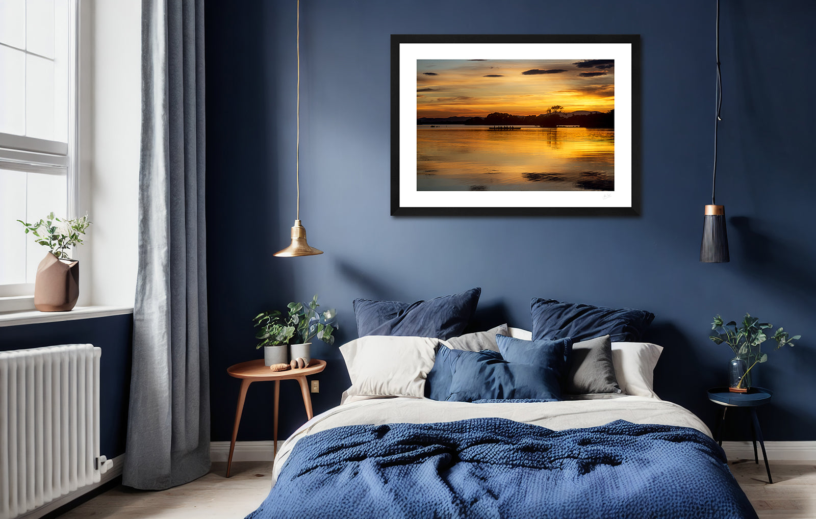 a framed fine art photographic print of a boat of rowers on Lough Leane, Killarney surrounded by the beautiful colours of a summer sunset, hanging on a wall above a bed